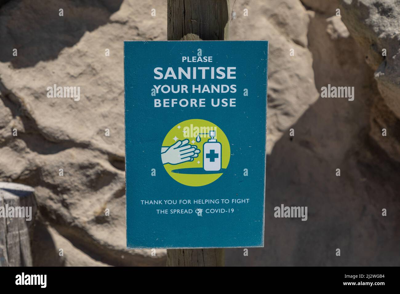 Sign reading Please sanitise your hands before use , including a graphic of hands being sanitised. Stock Photo