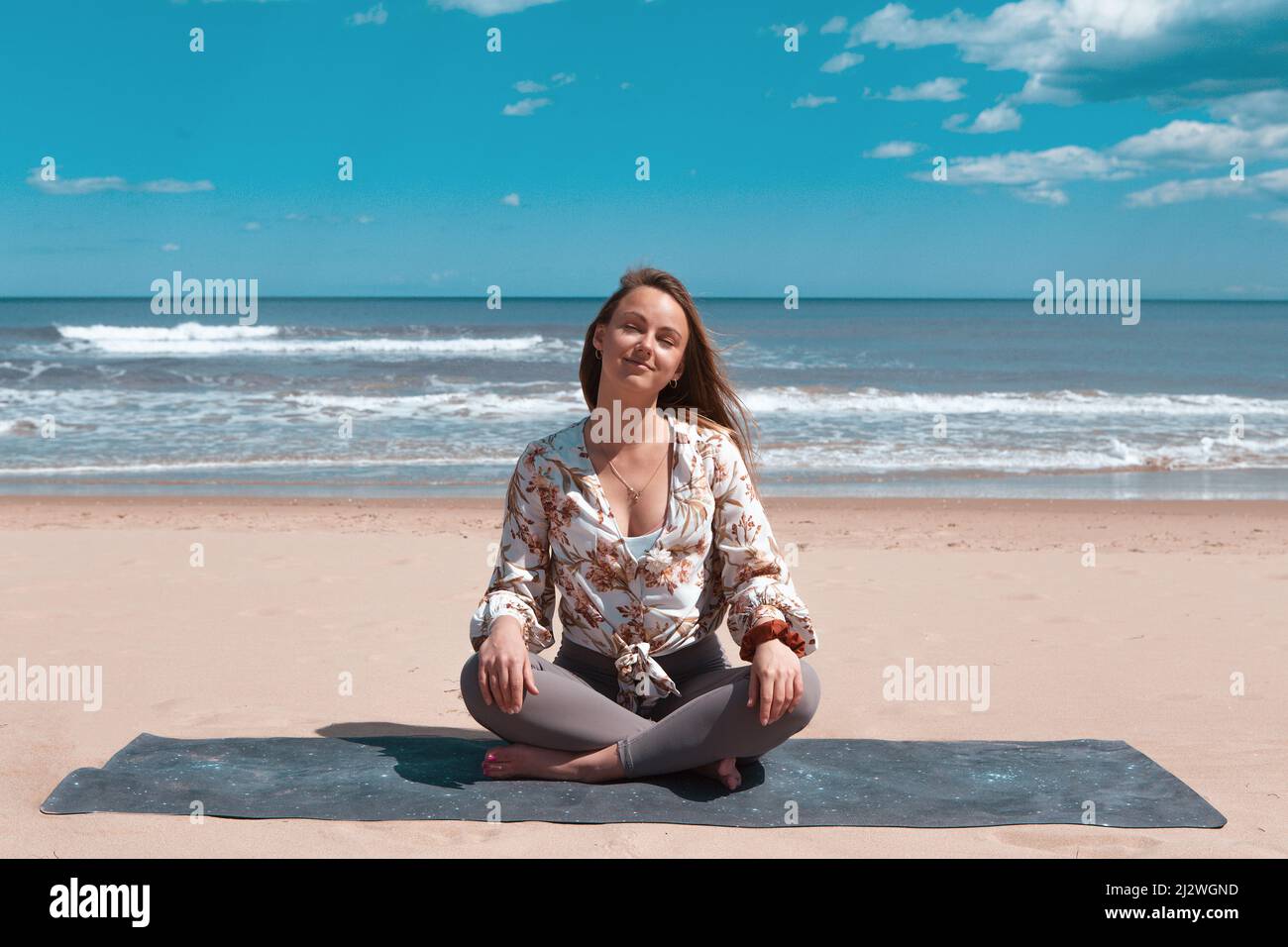 young blond woman on the beach doing pilates, yoga Stock Photo