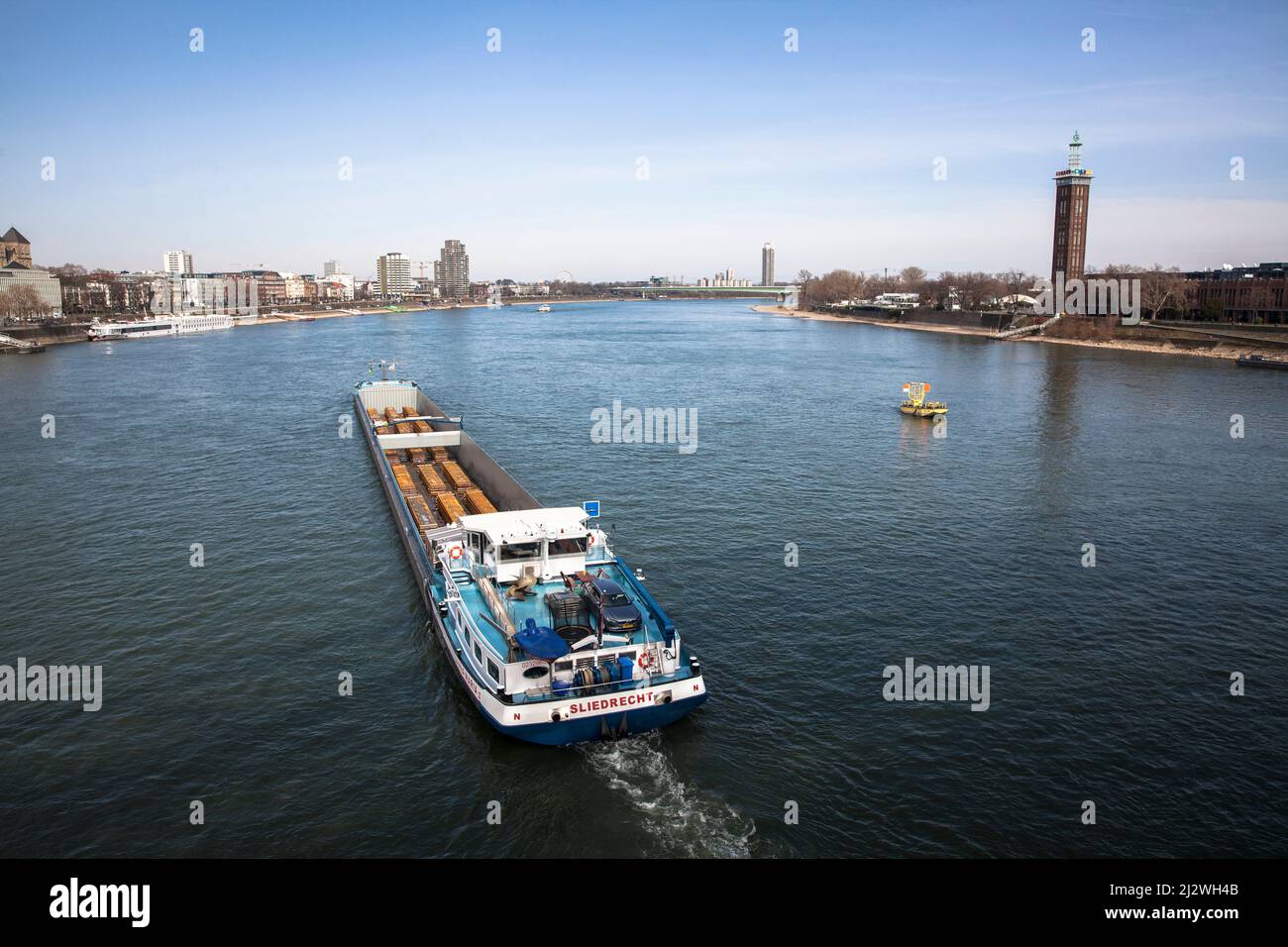 cargo ship with steel slabs on the Rhine, view to the old tower of the former exhibition center, Cologne, Germany. Frachtschiff mit Stahlbrammen auf d Stock Photo
