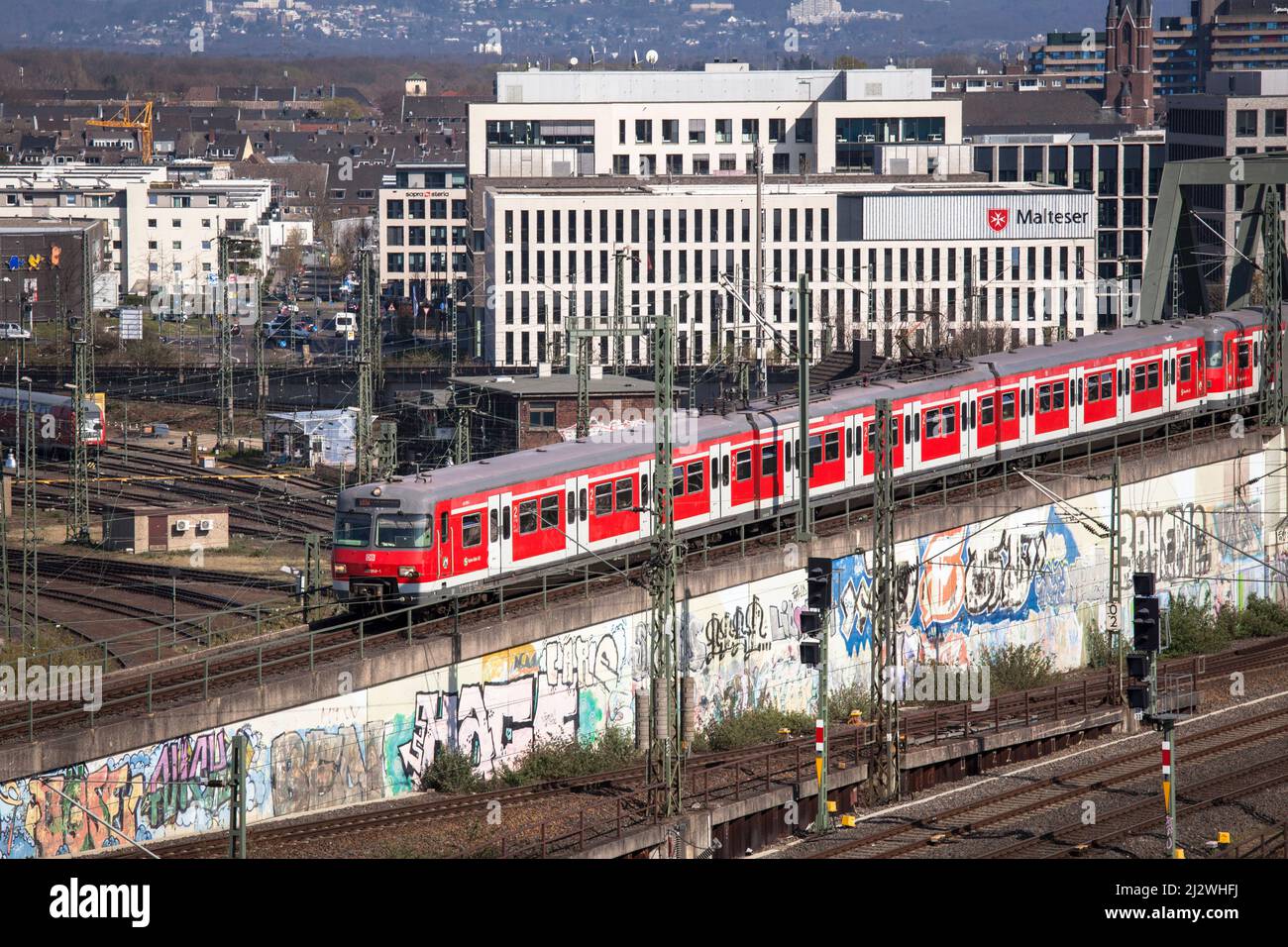 S-Bahn Rhein-Ruhr local train in the town district Deutz, in the background the headquarters of the Malteser Hilfdienst (MHD), Cologne, Germany. Zug d Stock Photo