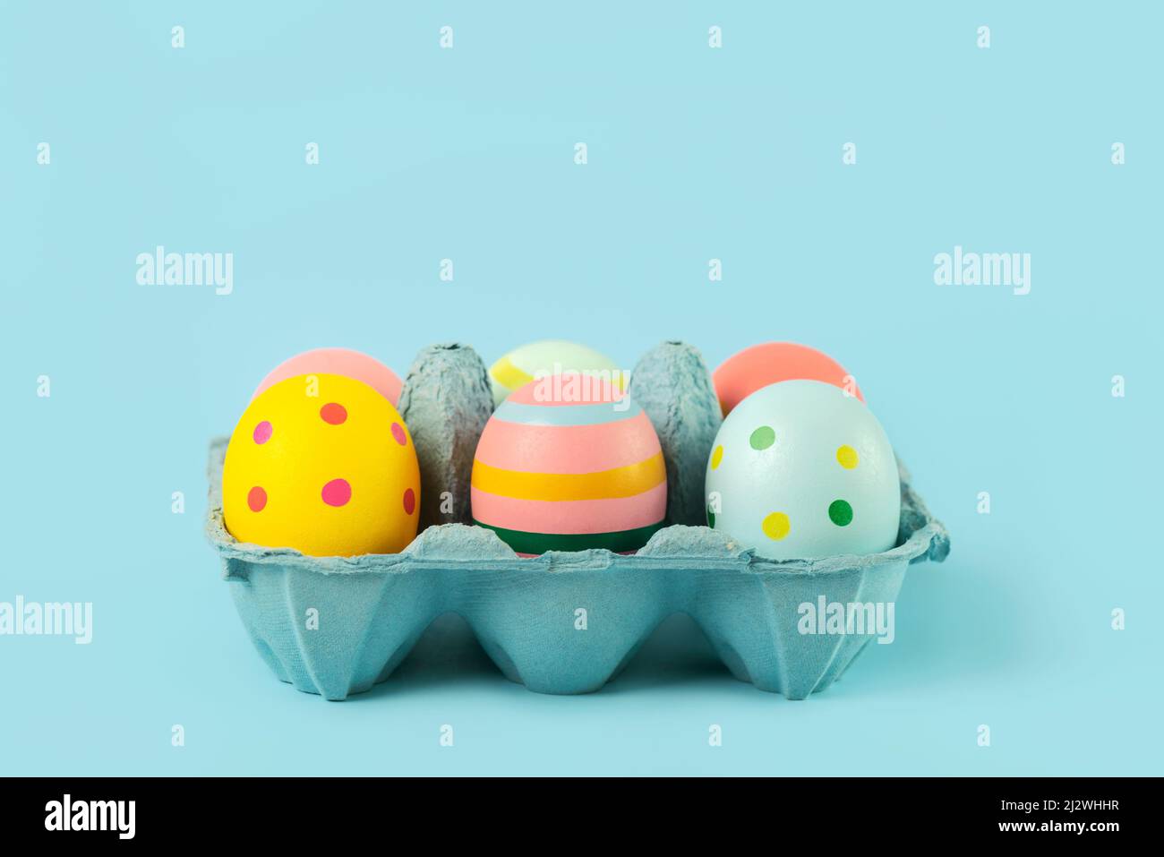 Happy Easter. Easter painted eggs in an open blue cardboard box over blue background Stock Photo