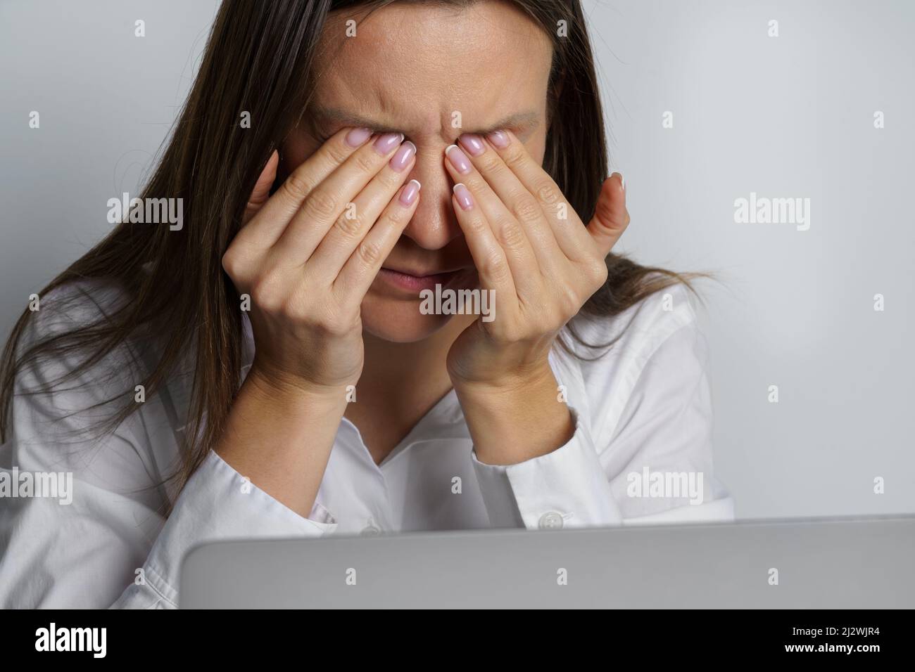 Tired woman suffering from eyes pain after working on the computer