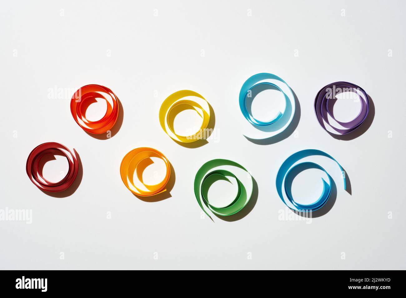 Rainbow colored paper circles on white background. Multicolor spirals pride Stock Photo