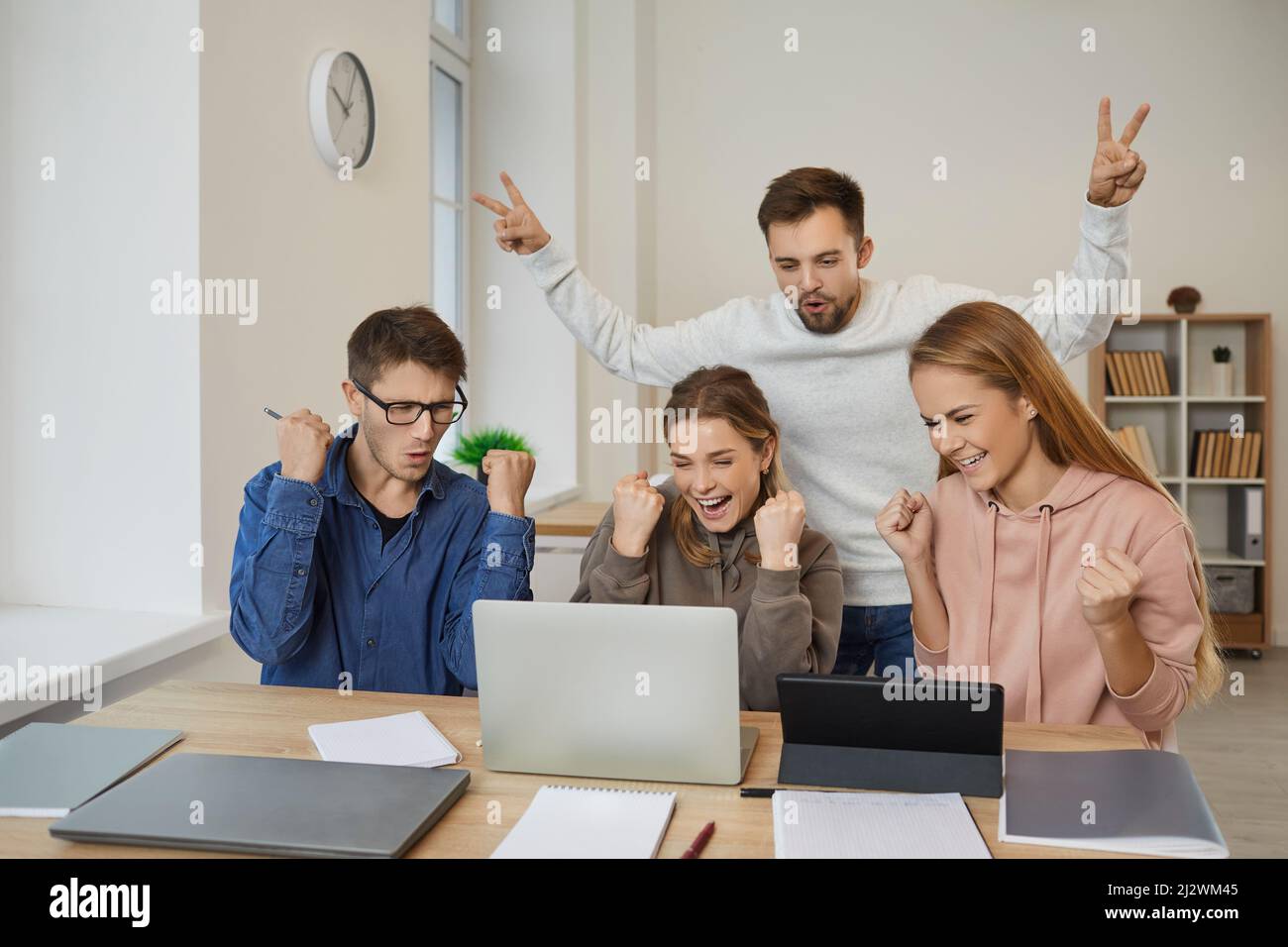 Smiling diverse young people triumph with news on computer Stock Photo