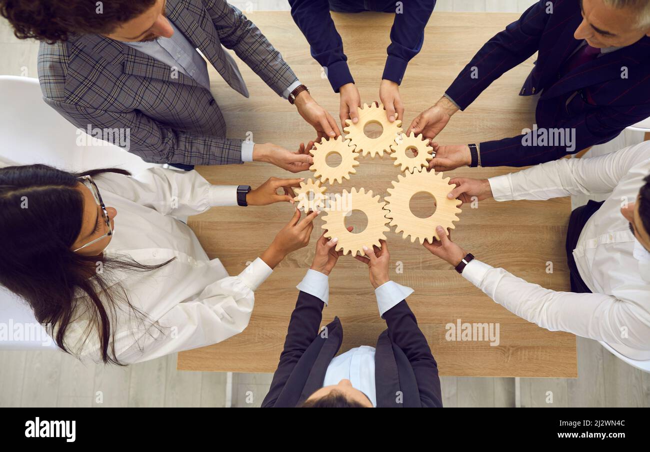 People stacking wooden gears next to each other, symbolizing development and success. Stock Photo
