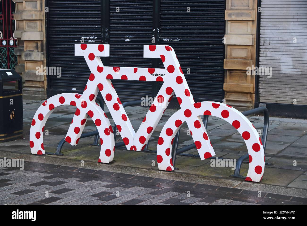 Model of bicycle painted white with red polka dots at bicycle parking frame, Halifax, West Yorkshire Stock Photo