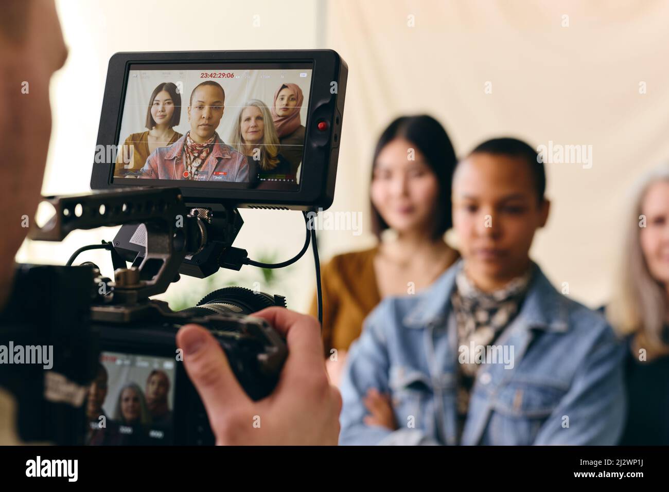 Videographer filming group of multiethnic women for International Women's Day with digital image on camera screen Stock Photo