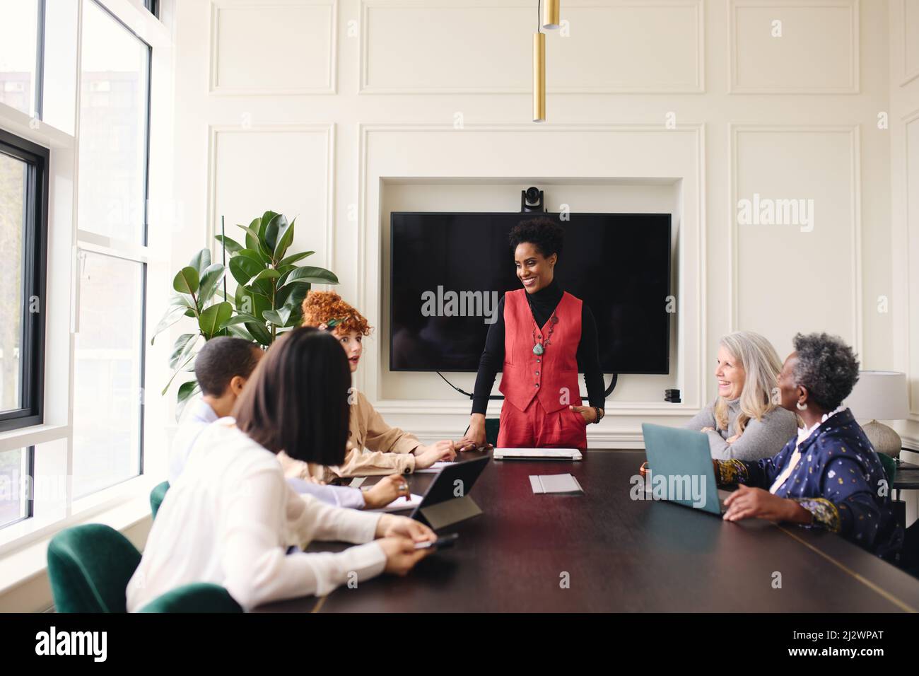 Portrait of cheerful mature black businesswoman discussing with female colleagues in meeting room Stock Photo