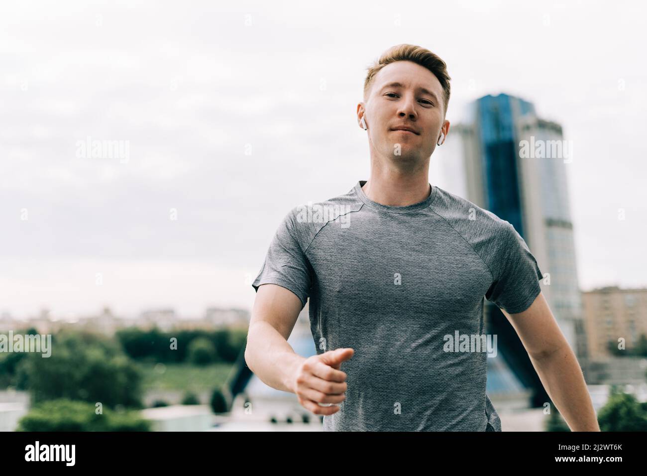 Young athlete man runner running up and down on city stairs in summer on morning run, background urban city street. Sports training. Fitness cardio Stock Photo