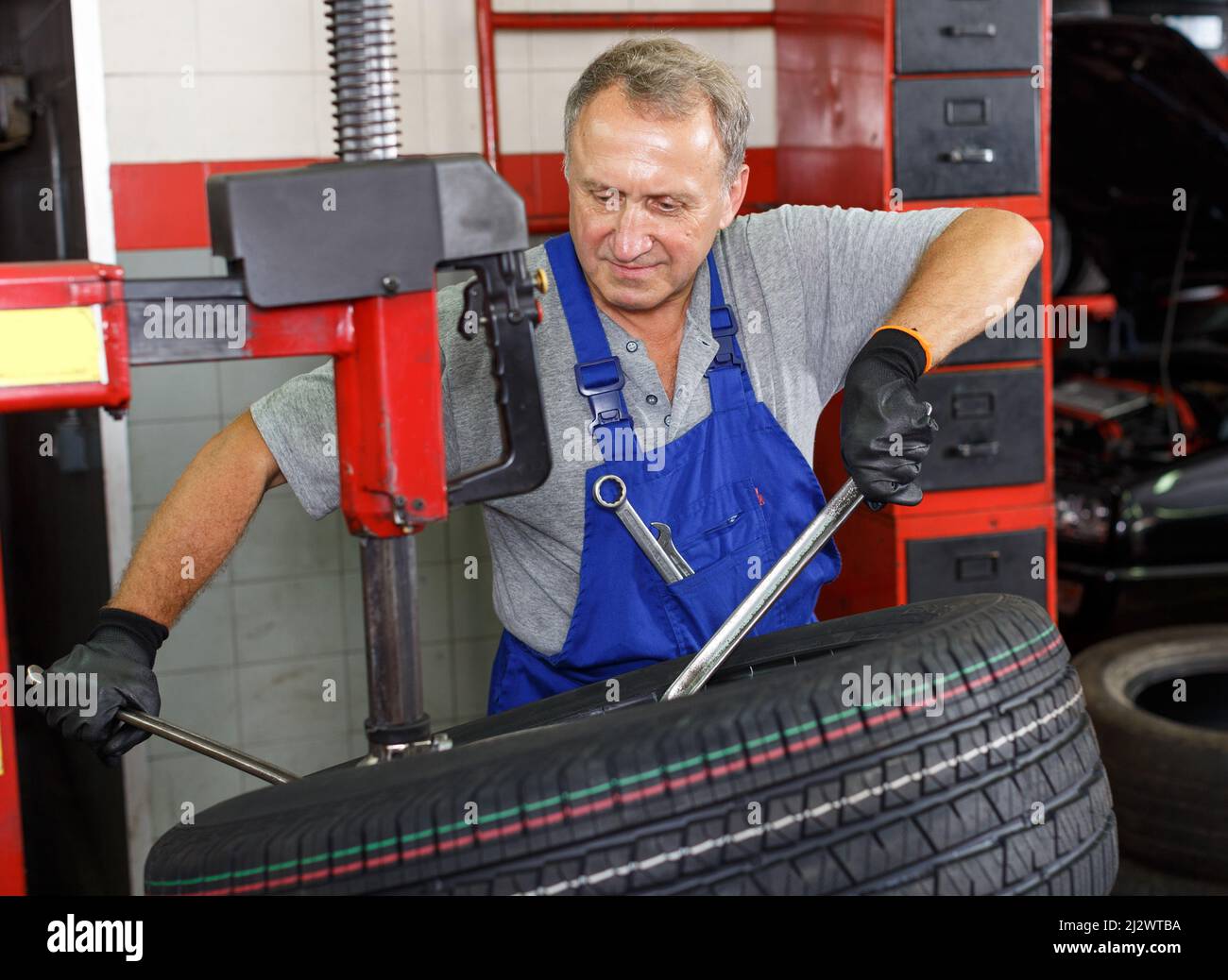 Mechanic preparing car wheel for balancing Stock Photo - Alamy