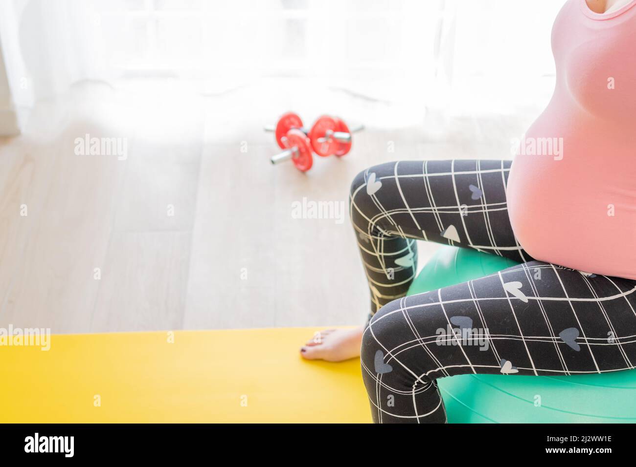 young pregnant woman sitting on a fitness ball doing sports to stay