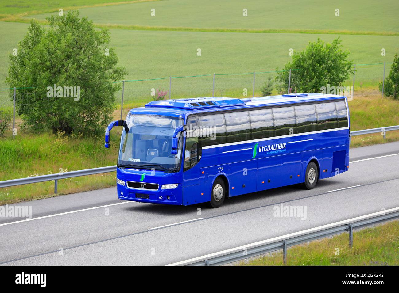 Bright blue Volvo bus Bygdaleidir, Finland plates, on Finnish National Road 1, E18, in South of Finland. Salo, Finland. July 10, 2020. Stock Photo