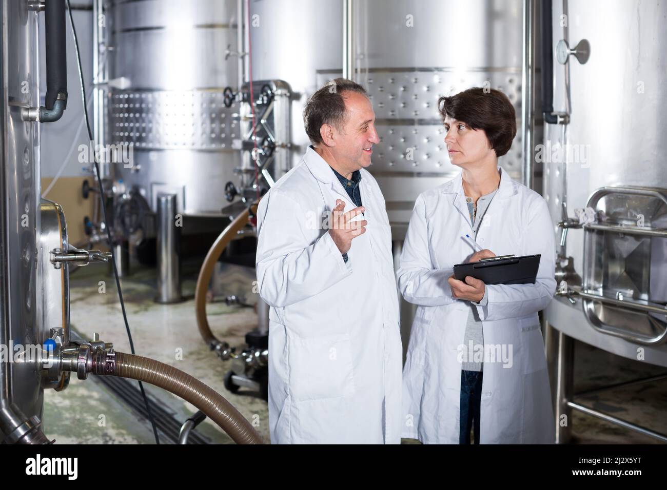 Adult glad wine maker shows to expert equipment on winery Stock Photo