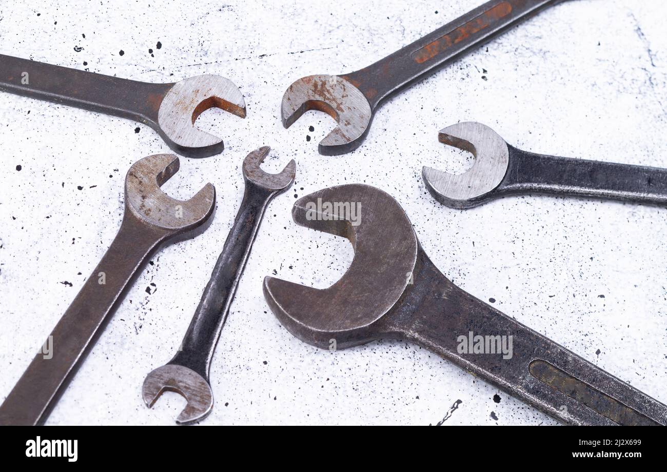 The photo shows various rusty wrenches on a light gray background Stock Photo