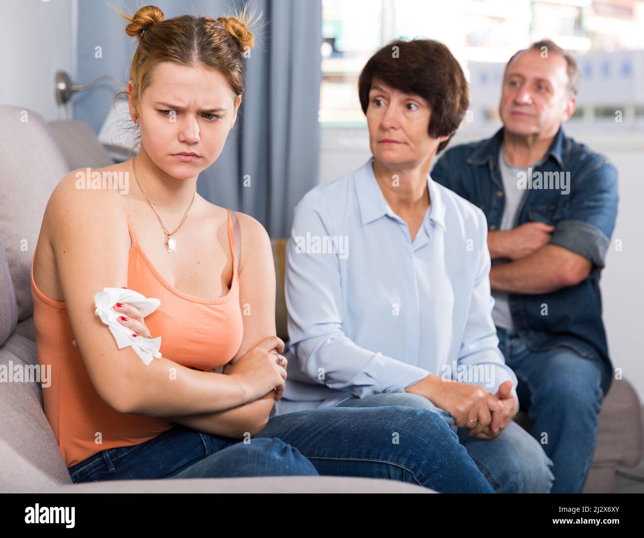 Mom and dad are supporting a sad daughter on sofa at home Stock Photo ...