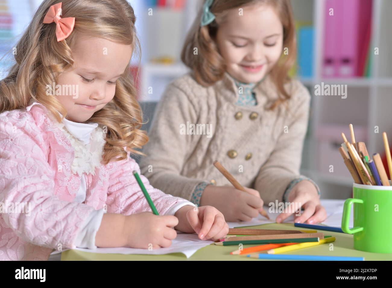 Two cute little girls drawing with pencils Stock Photo - Alamy