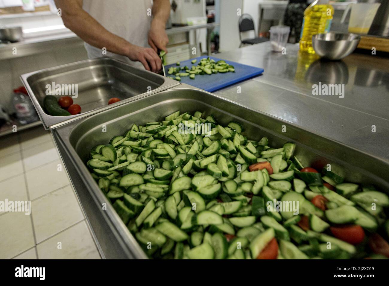 KYIV, UKRAINE - APRIL 1, 2022 - A cook slices cucumbers as nearly 400 meals for Territorial Defence Forces, Ukrainian Railways workers, sappers, borde Stock Photo