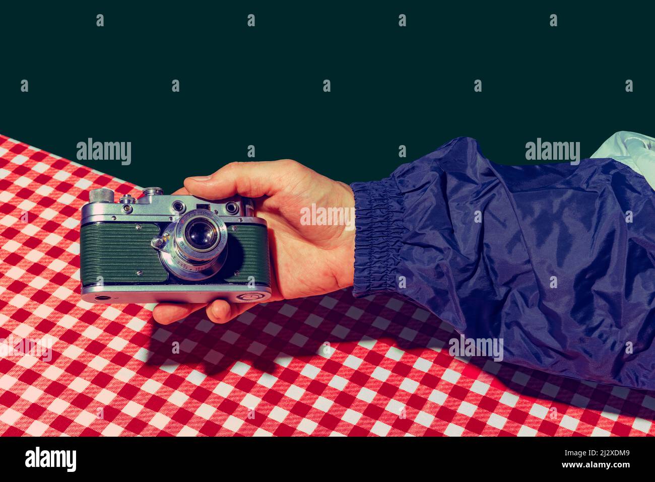 Concept of pop art photography. Using retro gadgets. Human hand holding photo camera isolated on green background. Vintage fashion style. Concept of Stock Photo
