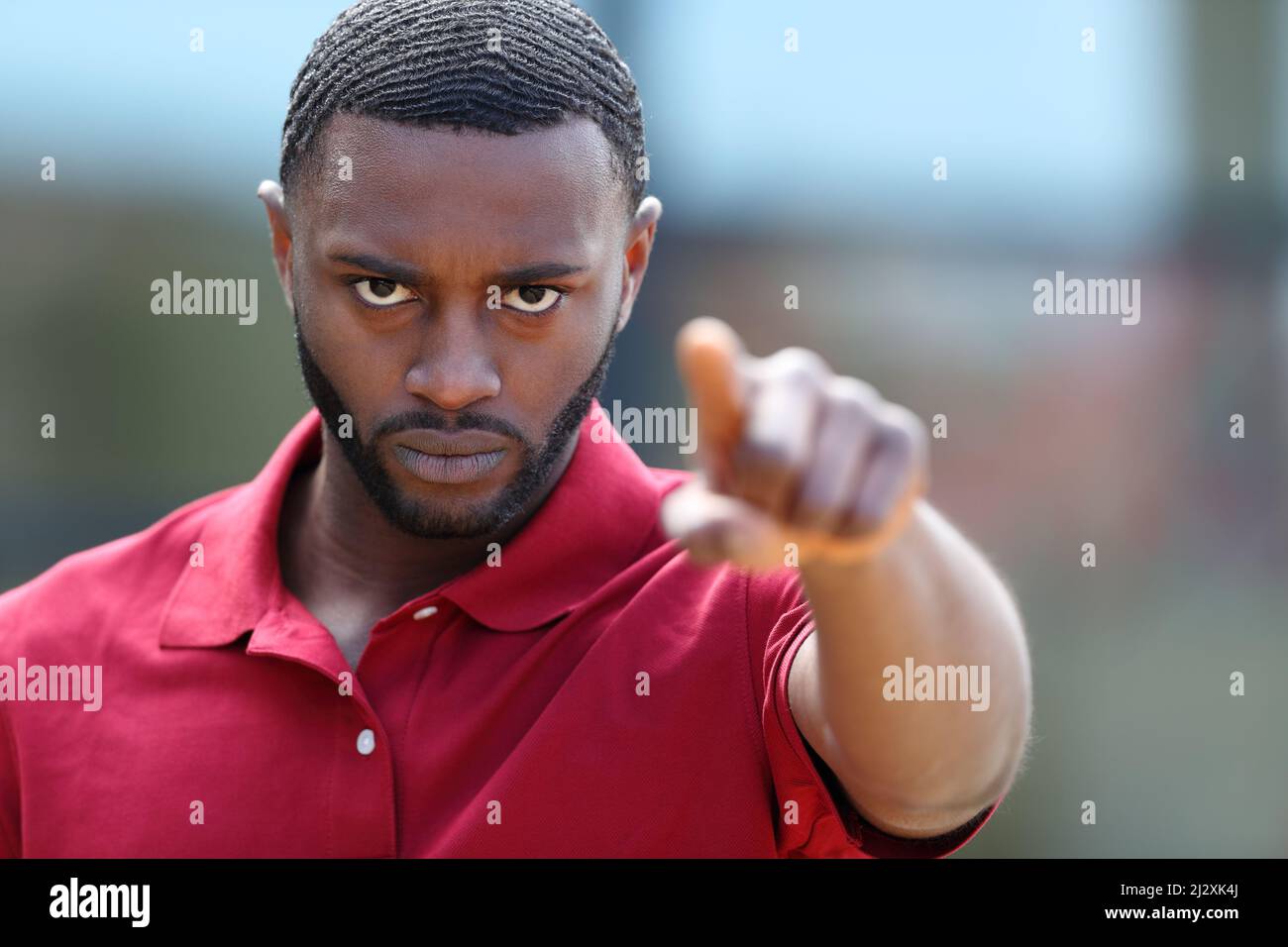 Front view portrait of a angry man with black skin pointing at camera in the street Stock Photo
