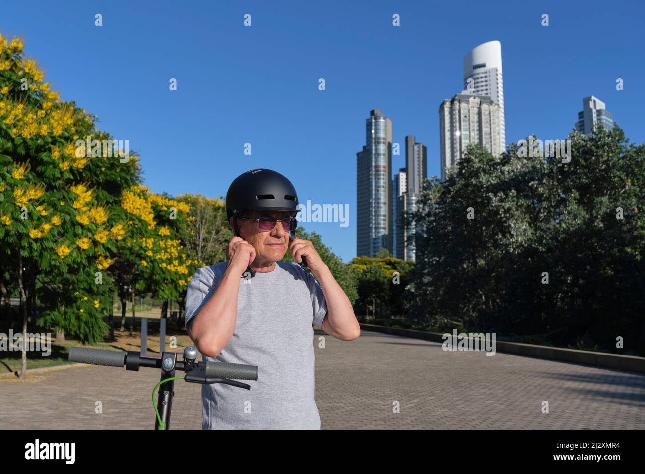 Latin senior man putting on a sports helmet to ride his electric kick