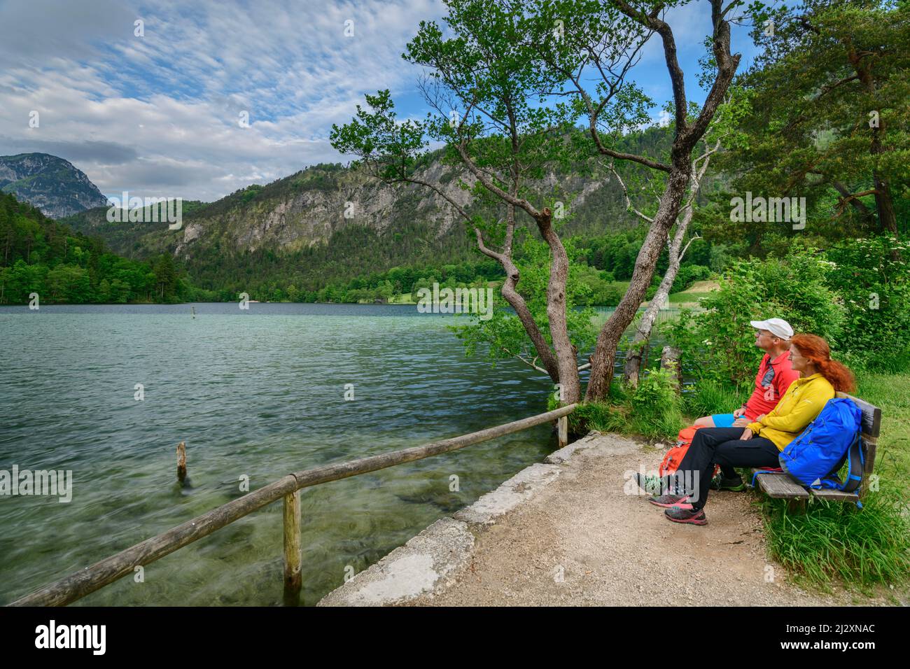 Man and woman while hiking sit on bench and look at Thumsee, Thumsee, Berchtesgaden Alps, Salzalpensteig, Upper Bavaria, Bavaria, Germany Stock Photo