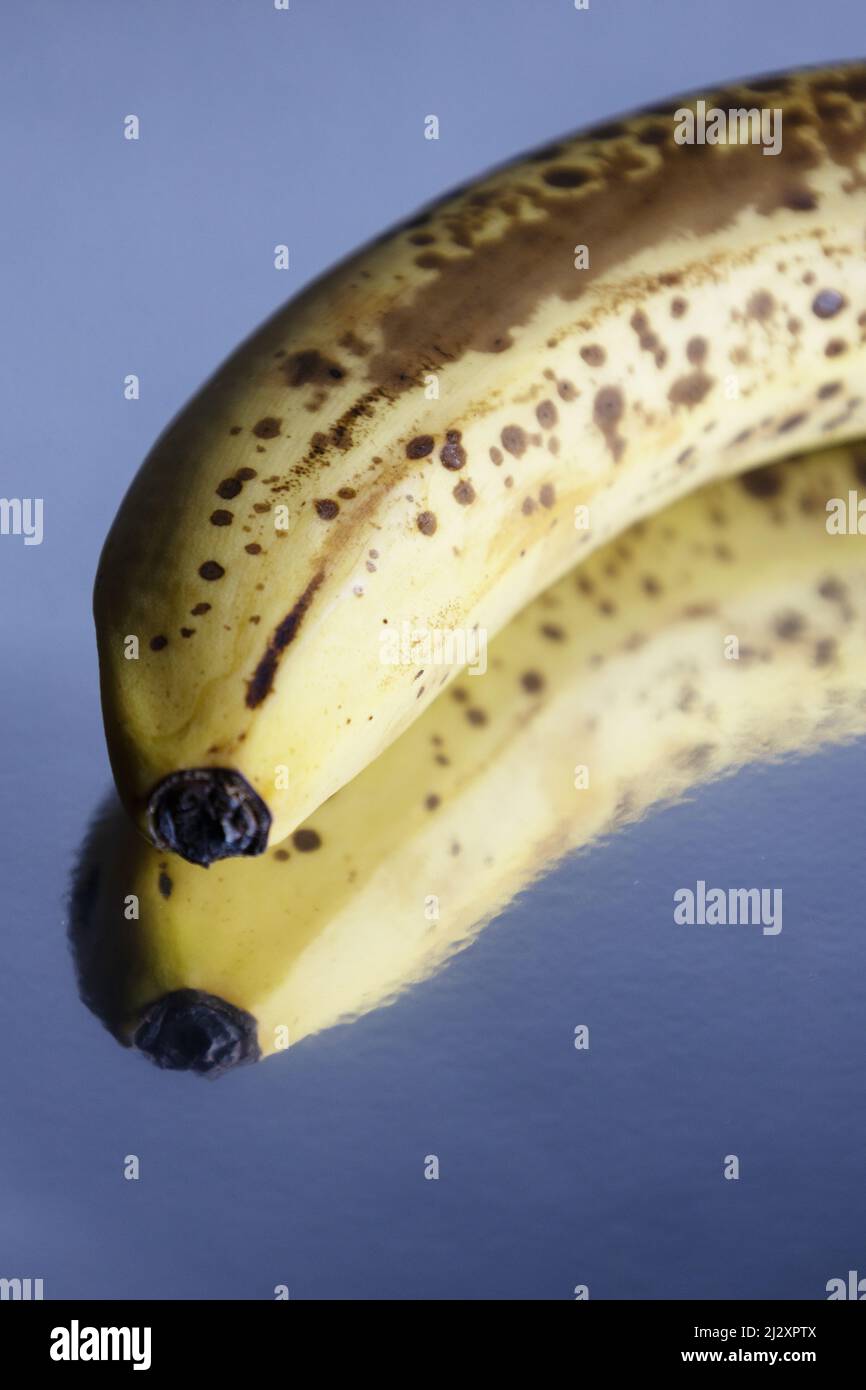 A brown speckled banana on a reflective background. Stock Photo