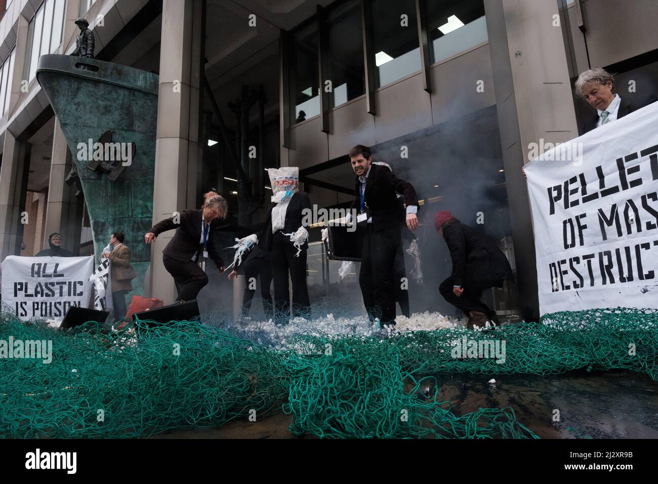 London, UK. 4th Apr, 2022. Members of Ocean Rebellion, perform creative theatrical action at the London Headquarters of the International Maritime Organization (IMO) on the morning of day 1 of the IMO pollution prevention and response conference, suited members of Ocean Rebellion spilled fake ‘nurdles', and oil amongst the discarded fishing waste and black carbon and plastic bag people while a pair of dirty scrubbers cleaners attempt to hide the evidence with their greenwash services. Credit: Joao Daniel Pereira/Alamy Live News Stock Photo