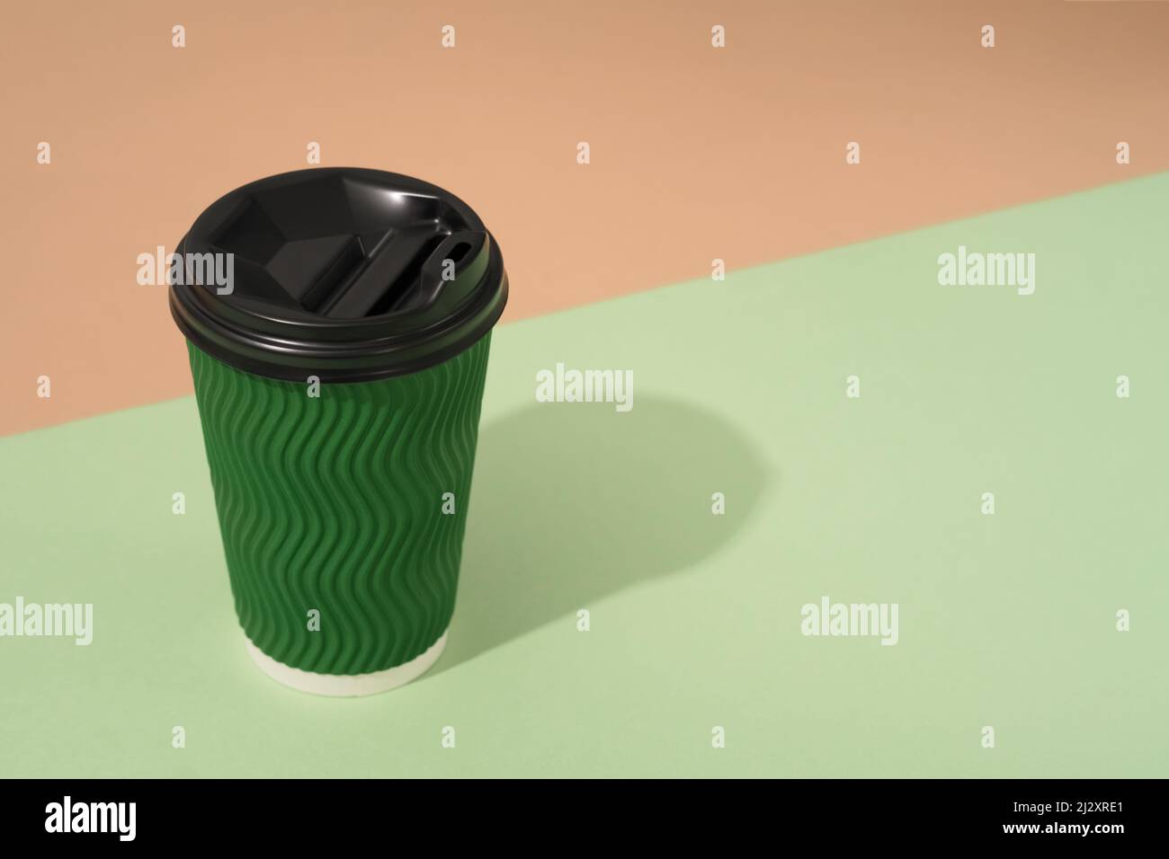 Green paper coffee cup on green and brown background with copy space ...
