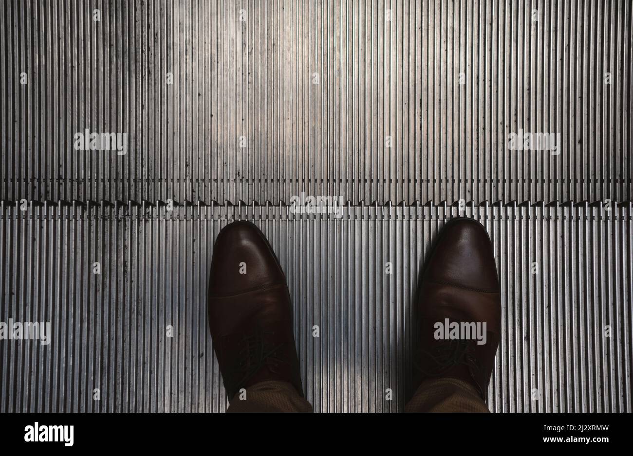 Detail of escalators with a focus on men's feet, shoe details Stock ...