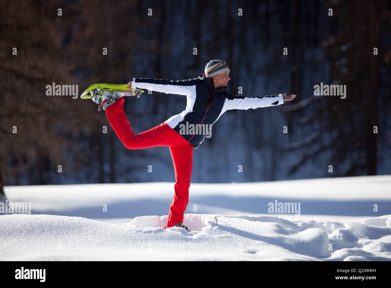 Serre-Chevalier (French Alps, south-eastern France): group of tourists during a hike with snowshoes. Woman practicing a yoga pose Stock Photo