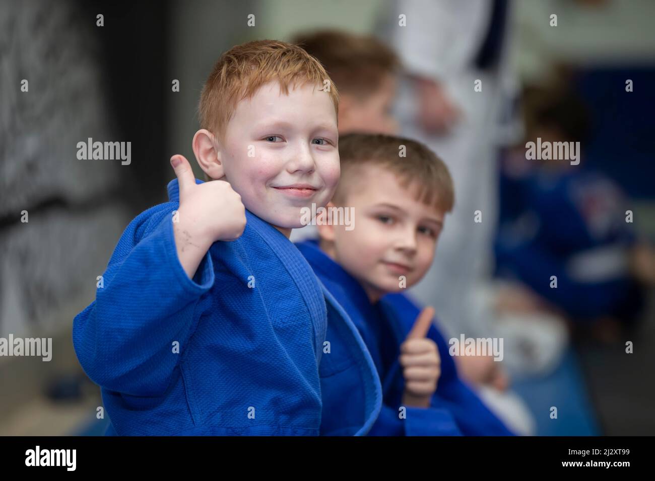 Judo school for children. Children judoists show the class sign with their fingers. Stock Photo