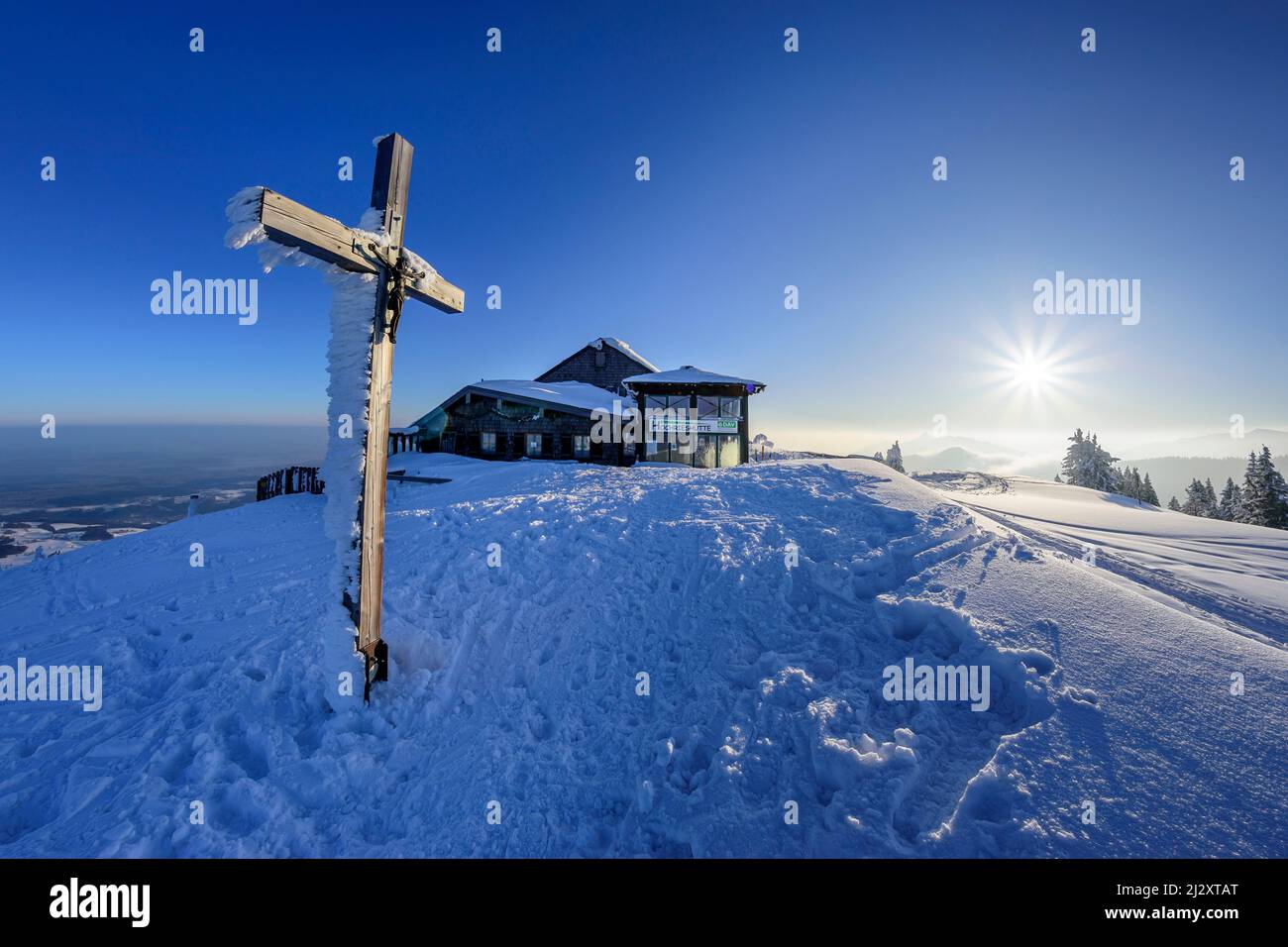 Snow-covered summit cross and Hochrieshütte on the summit of the Hochries, Hochries, Chiemgau Alps, Upper Bavaria, Bavaria, Germany Stock Photo