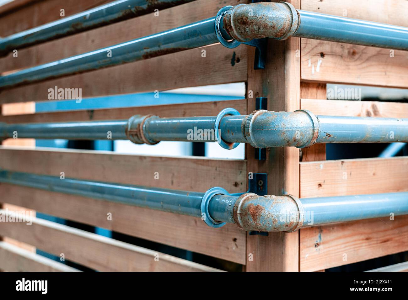 Blue pipes attached to wooden fence Stock Photo Alamy