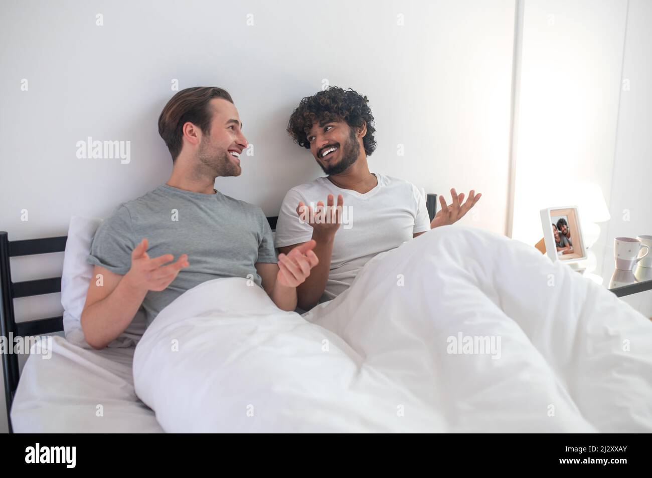 Gay couple talking to each other in their bedroom Stock Photo