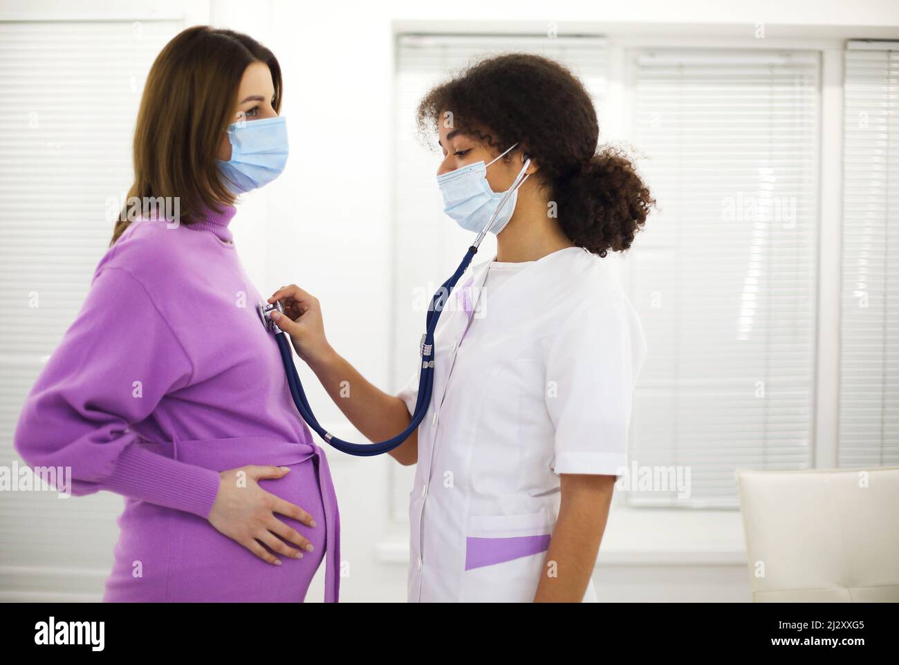 Doctor listening to pregnant woman heartbeat with stethoscope during