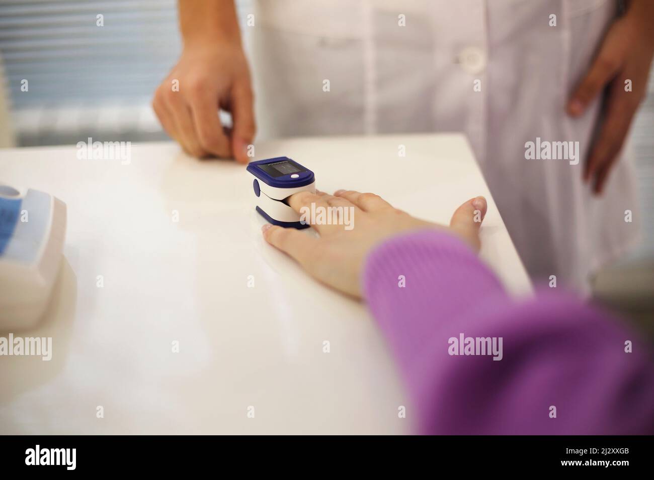Pregnant woman with pulse oximeter on finger. Doctor measuring oxygen