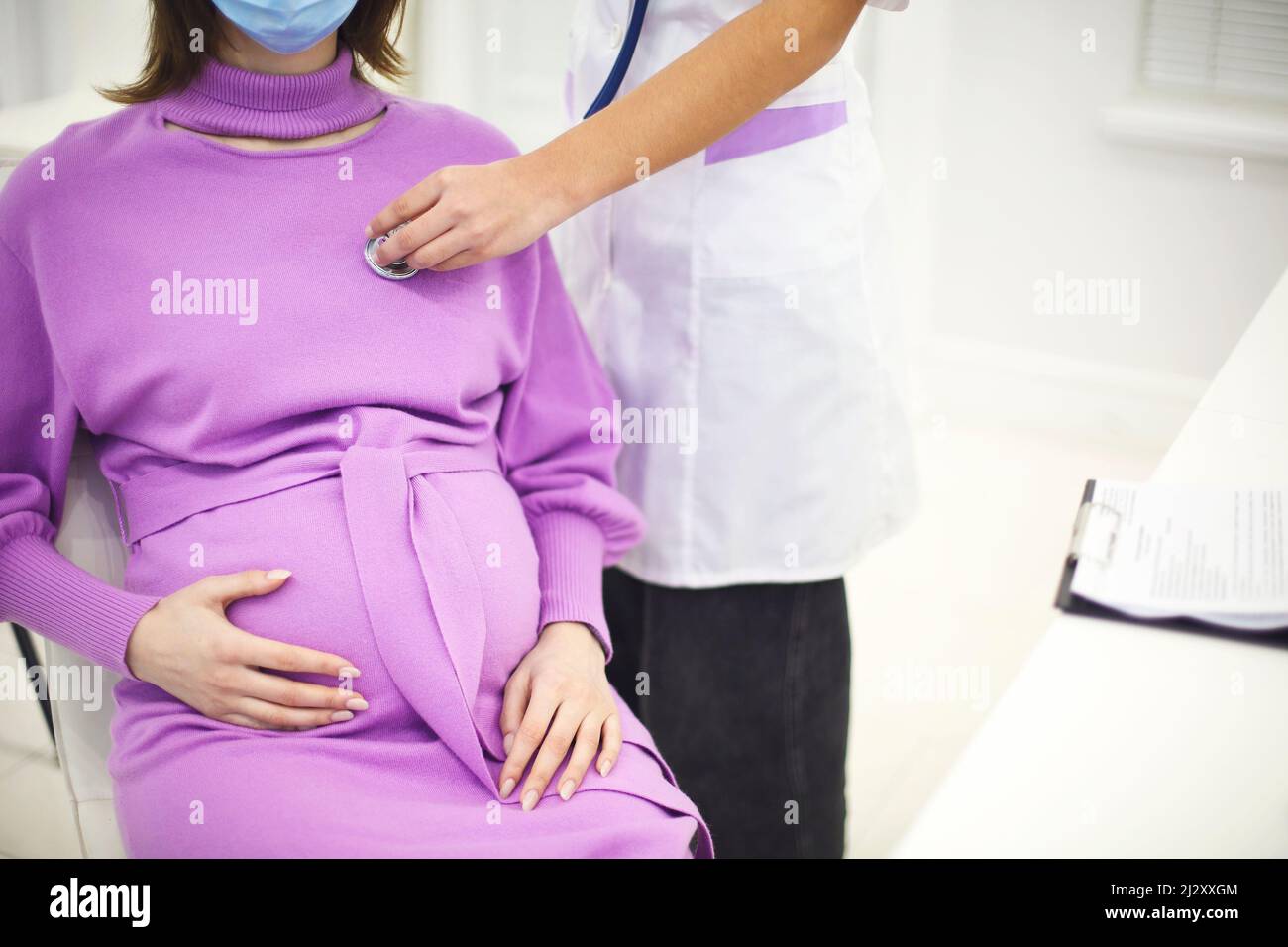 Doctor listening to pregnant woman heartbeat with stethoscope during