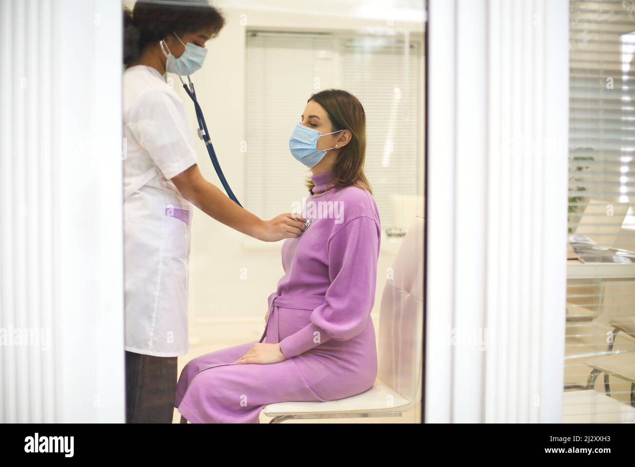 Doctor listening to pregnant woman heartbeat with stethoscope during