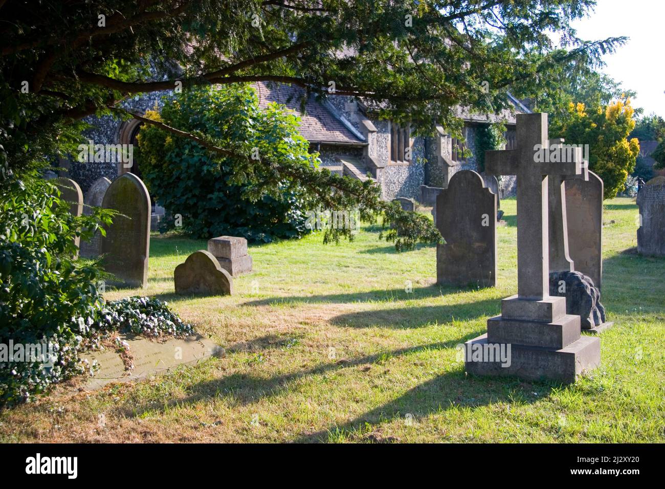 English Cemetery. A quiet countryside graveyard at dusk by a flint stone church in rural England. Stock Photo