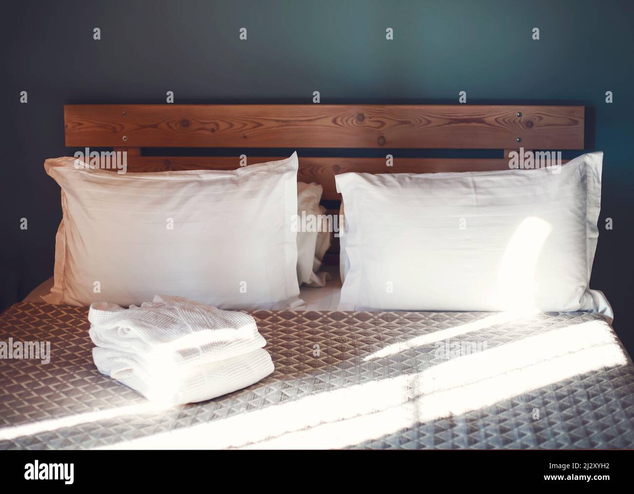 Two snow-white bath robes in sunlight, beautifully folded, lie on a bed ...