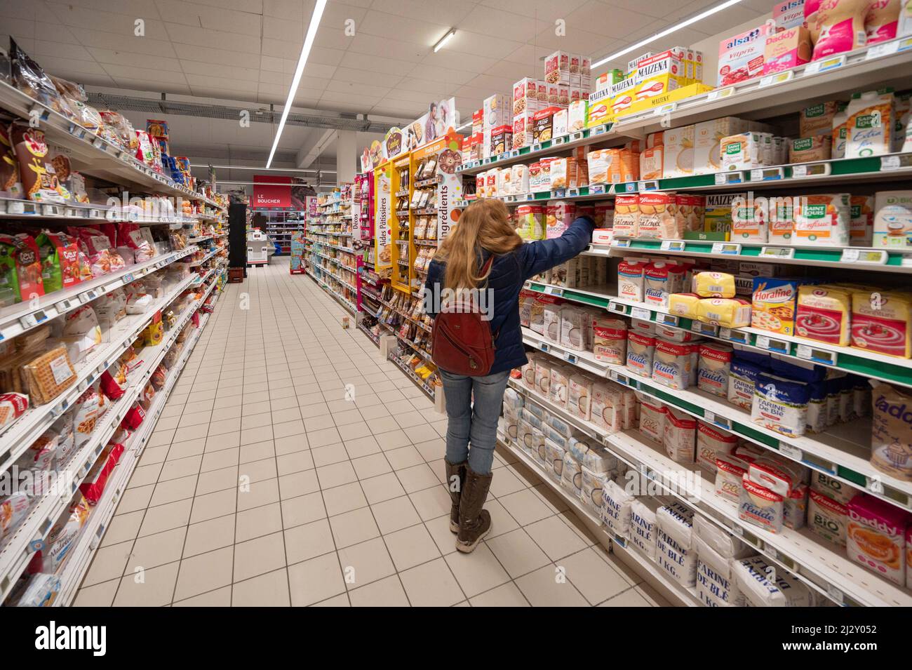 Super U supermarket: woman doing some shopping in the baking aisle, with flour on shelves Stock Photo