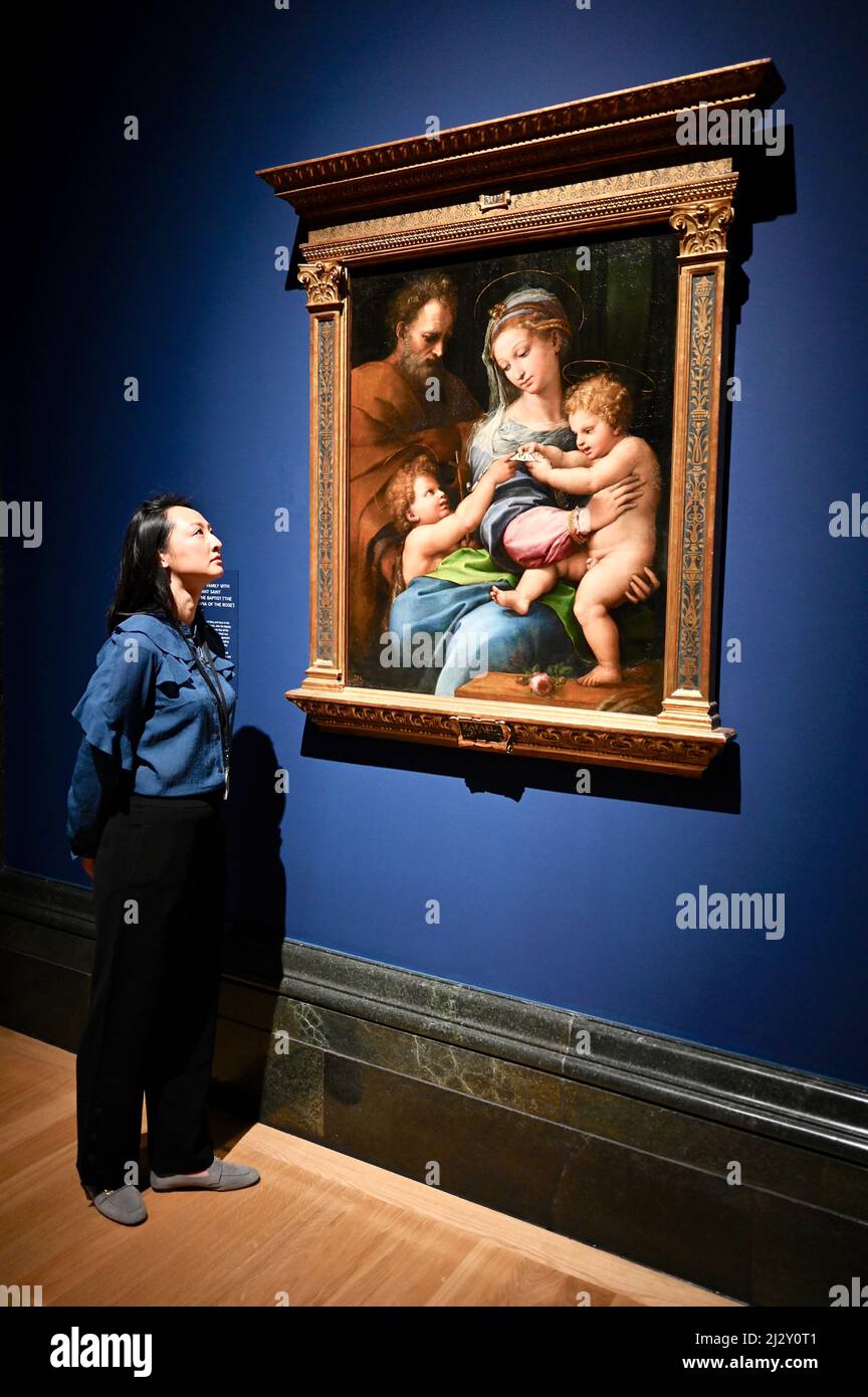 London, UK ( Embargoed till 00.01 on 6th April 2022.) A gallery employee views 'The Holy Family with the Infant Saint John the Baptist (The Madonna of the Rose'. The Credit Suisse Exhibition : Raphael. First Floor Galleries, The National Gallery, Trafalgar Square. Stock Photo