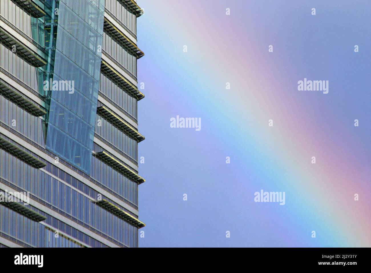 Skyscraper and rainbow. Detail of a contemporary London skyscraper reflecting the blue sky with a natural rainbow visible in the background. Stock Photo