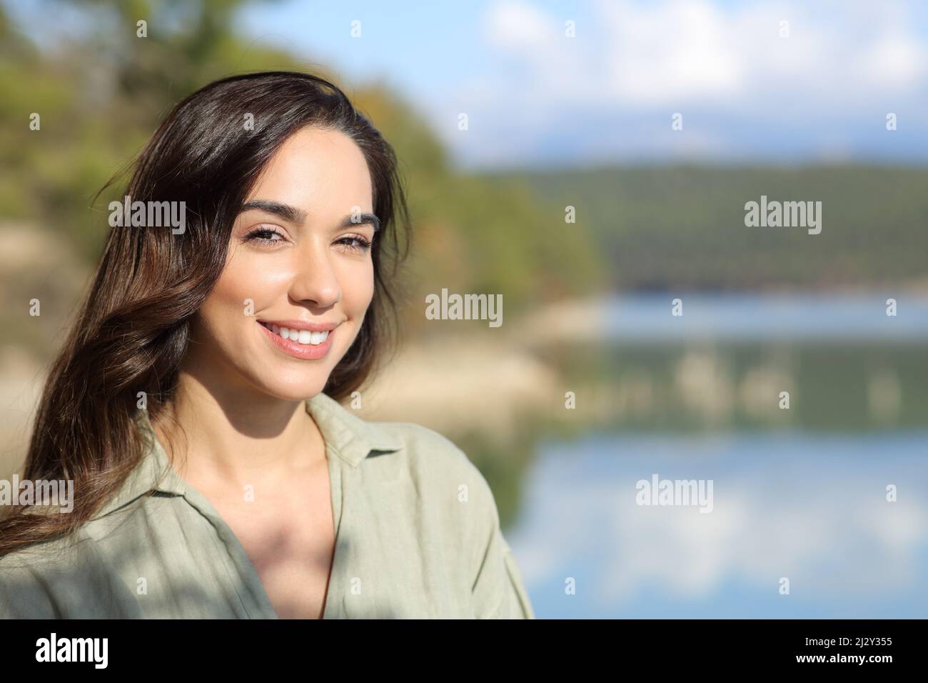 Happy woman looking at camera posing in a lake as sunny day Stock Photo