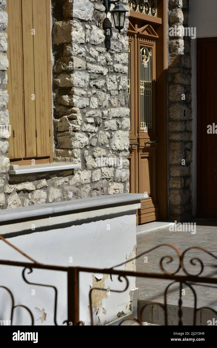 Traditional rural house facade with a stone wall, ochre wooden door and ...