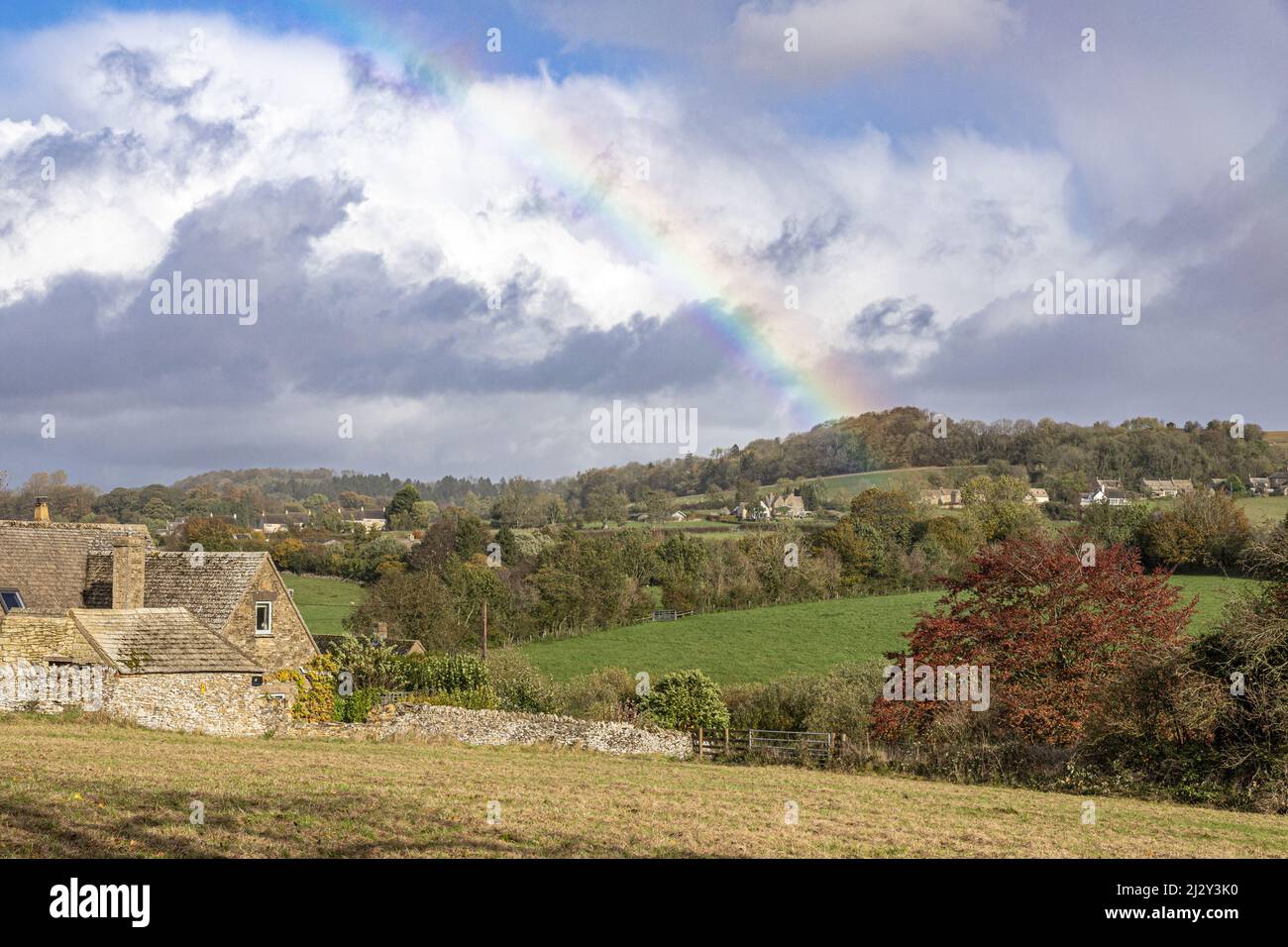 An autumn rainbow in the Cotswold village of Sevenhampton (looking towards Brockhampton), Gloucestershire, England UK Stock Photo