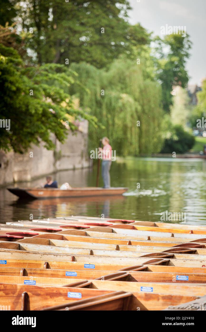 Shallow focus on the foreground punts throws the background Cambridge university buildings and students out of focus in this tranquil English scene. Stock Photo