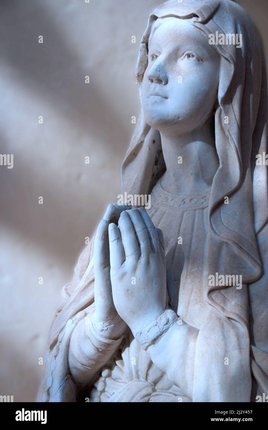 Moonlit Madonna. Moonlight falling on the face and hands of a statue of the Madonna at prayer. Stock Photo