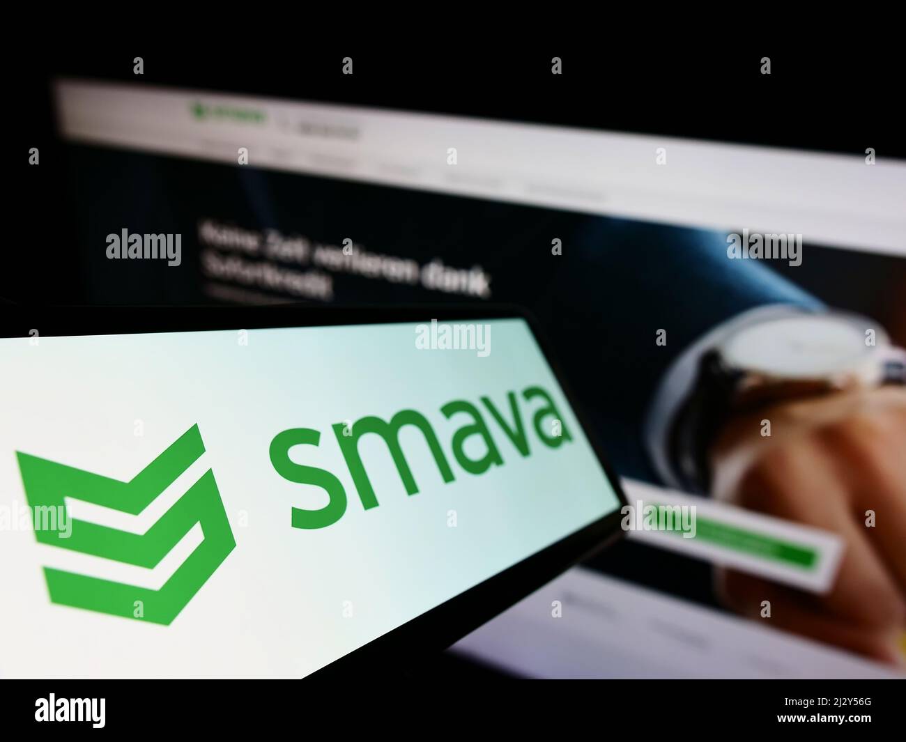 Cellphone with logo of German loan comparison company smava GmbH on screen in front of business website. Focus on left of phone display. Stock Photo