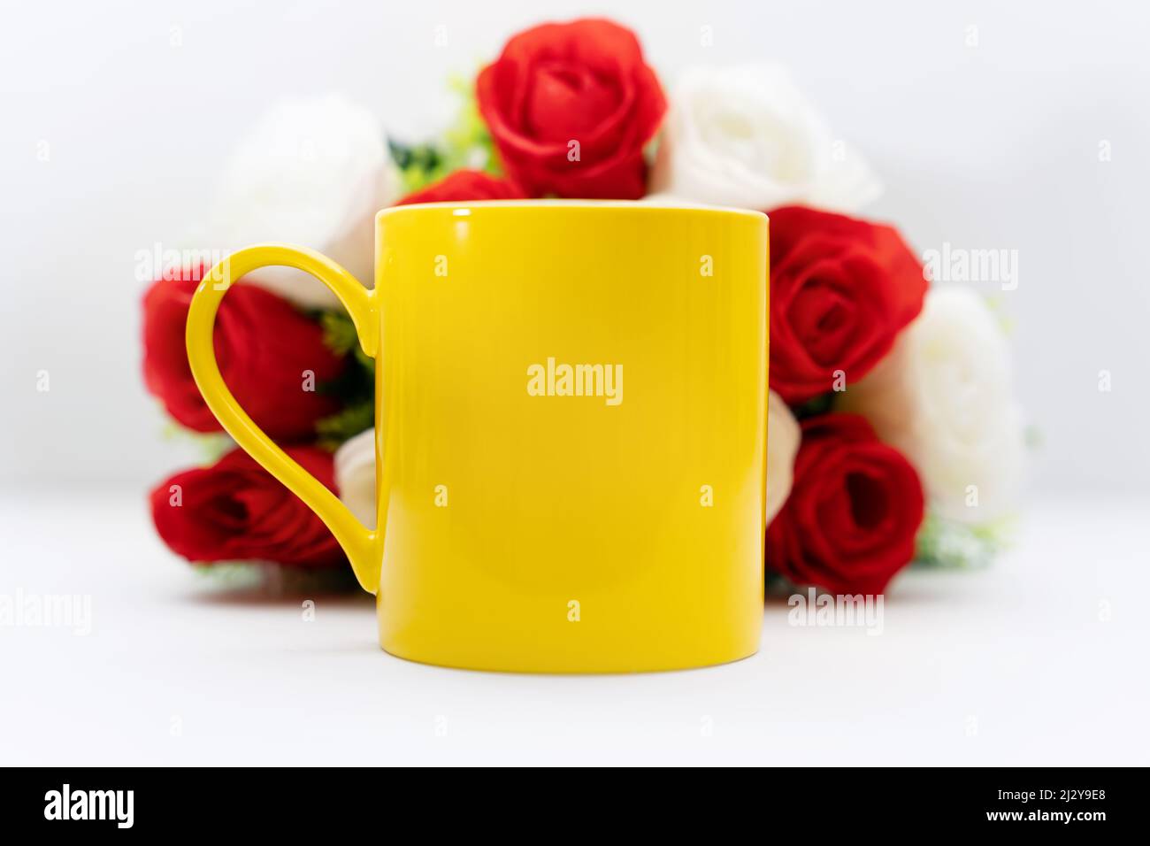 Vibrant Yellow Mug Againts Rose Flower Bouquet Stock Photo